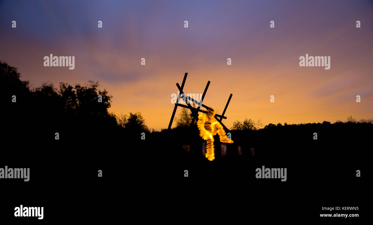 Une étrange figure rayonnante, est visible dans une pose réfléchie apparemment assis à l'extérieur dans le noir, avec un ciel au-dessus de l'atmosphère. Banque D'Images