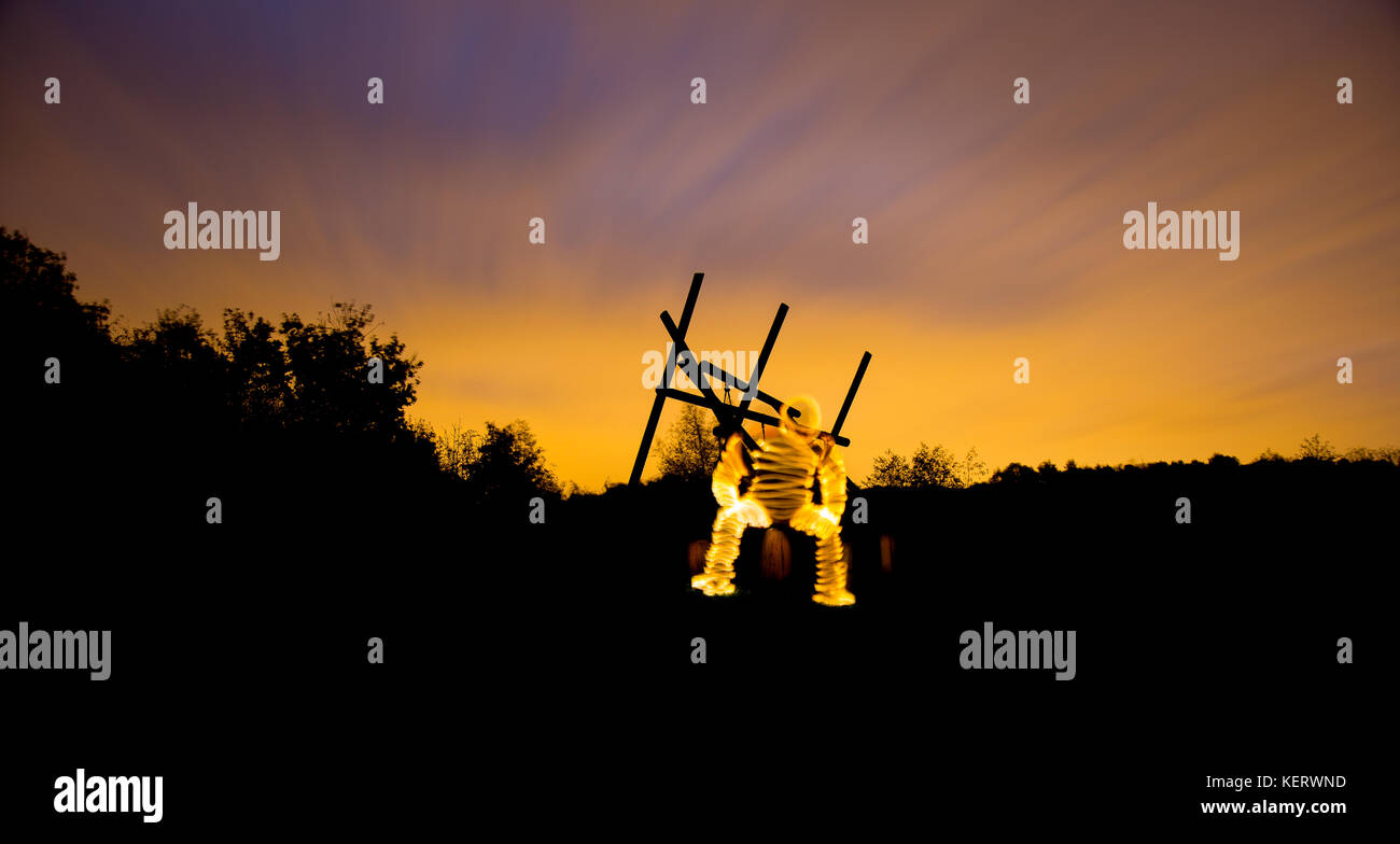 Étrangement, une étrange figure rougeoyante est visible à l'extérieur assis dans l'obscurité. Un ciel atmosphérique annonce la fin de la journée. Banque D'Images