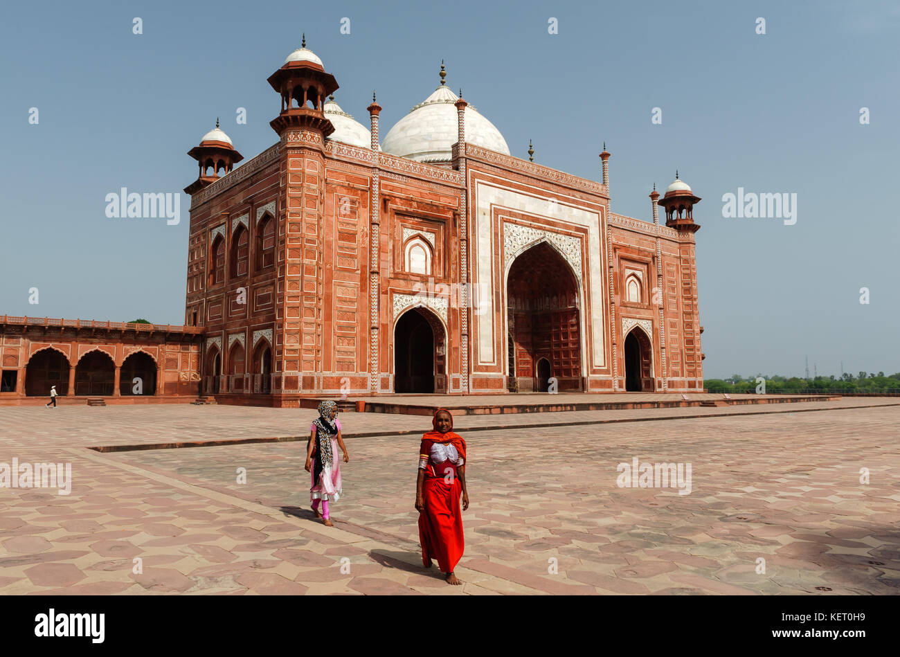 Femme en rouge la marche en face de la mosquée flanquant le Taj Mahal, l'Inde, Uttar Pradesh Banque D'Images