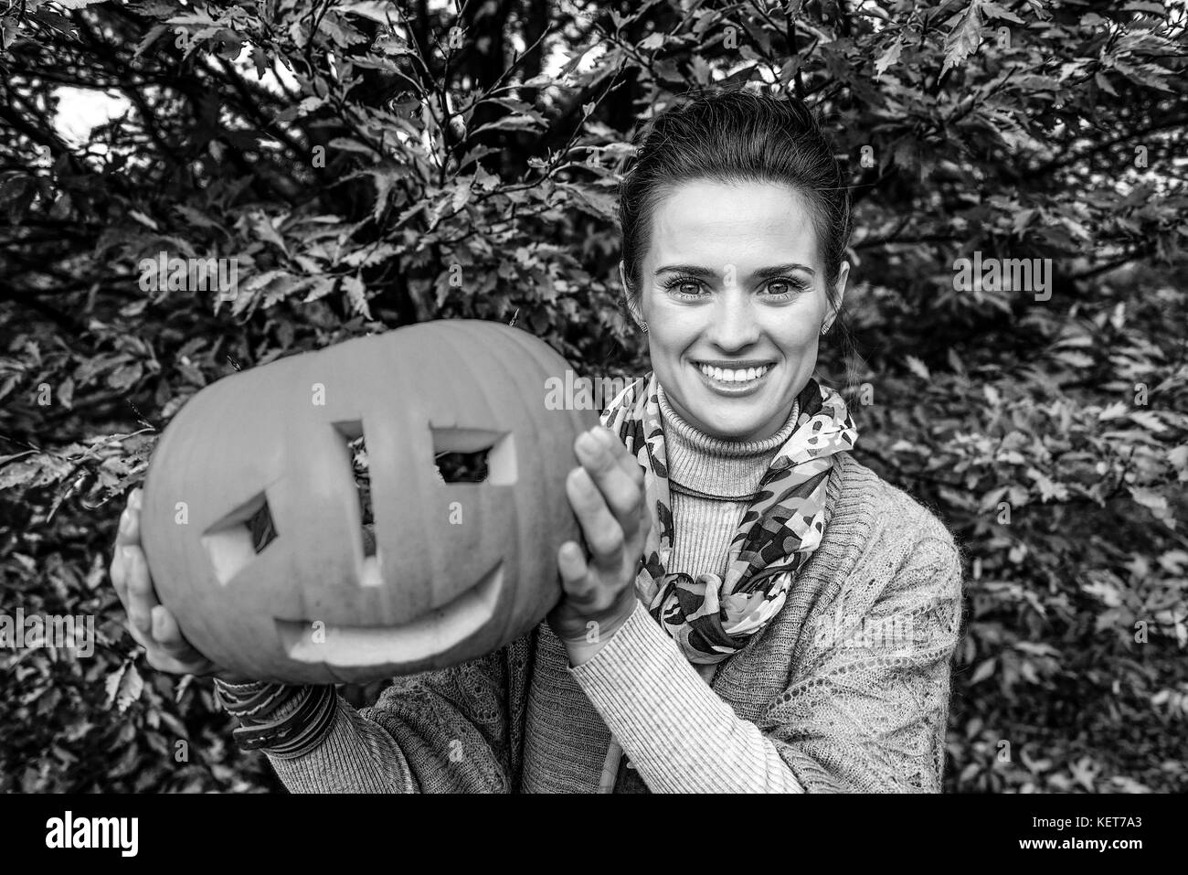 Trick or Treat. smiling femme moderne sur l'halloween à la citrouille sculptée montrant parc Banque D'Images