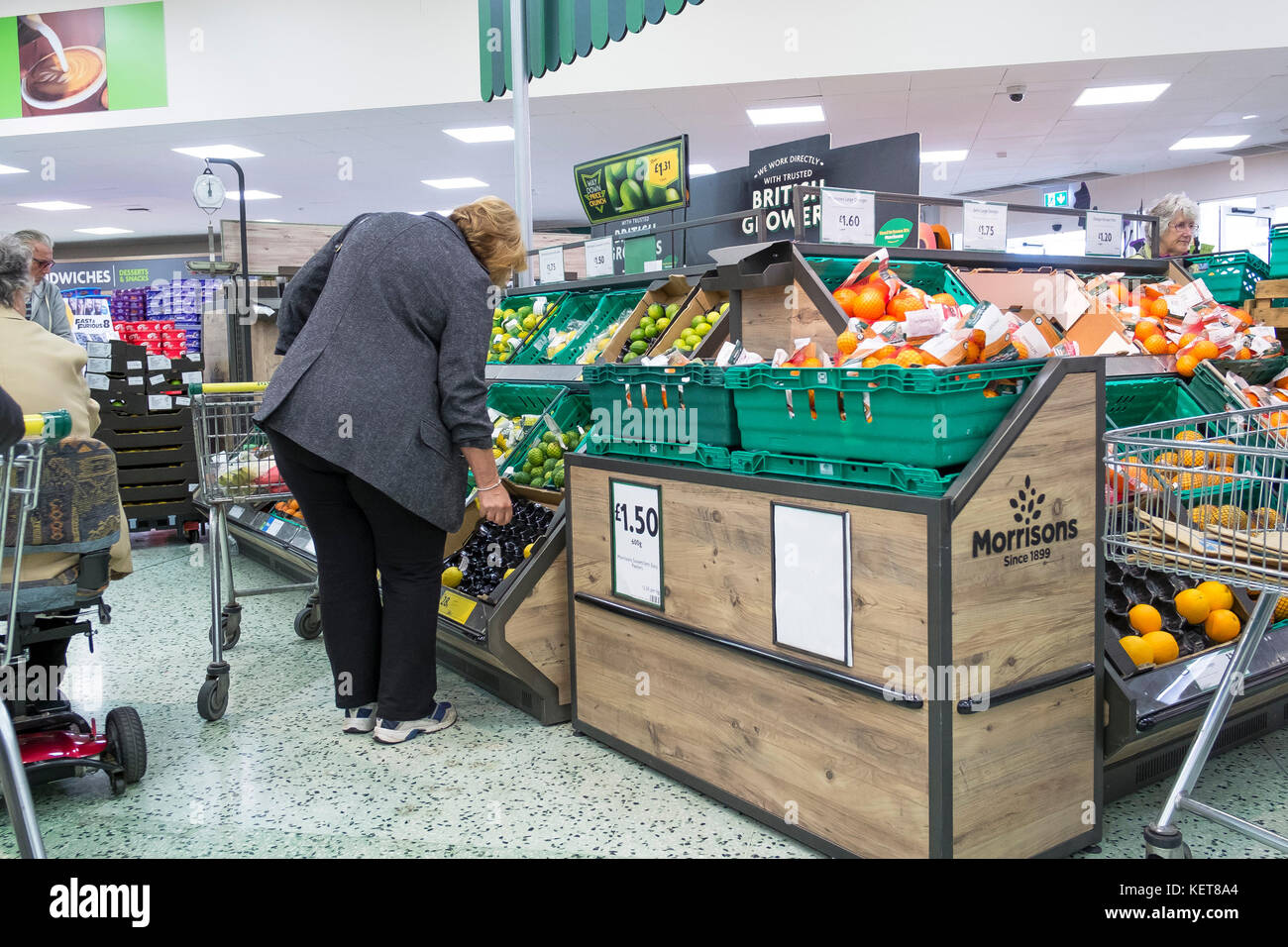 Shopping dans un supermarché Morrisons - un client à la recherche de l'affichage de fruits frais dans un supermarché Morrisons. Banque D'Images
