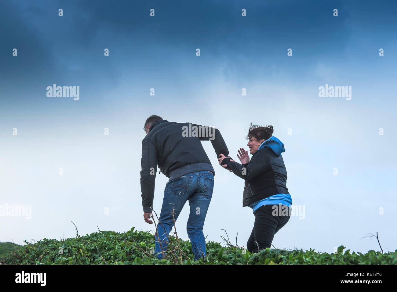 Météo britannique Brian Storm - un couple marchant dans les vents de tempête stormforce comme Brian apporte des conditions météorologiques au nord de la côte de Cornwall. Banque D'Images