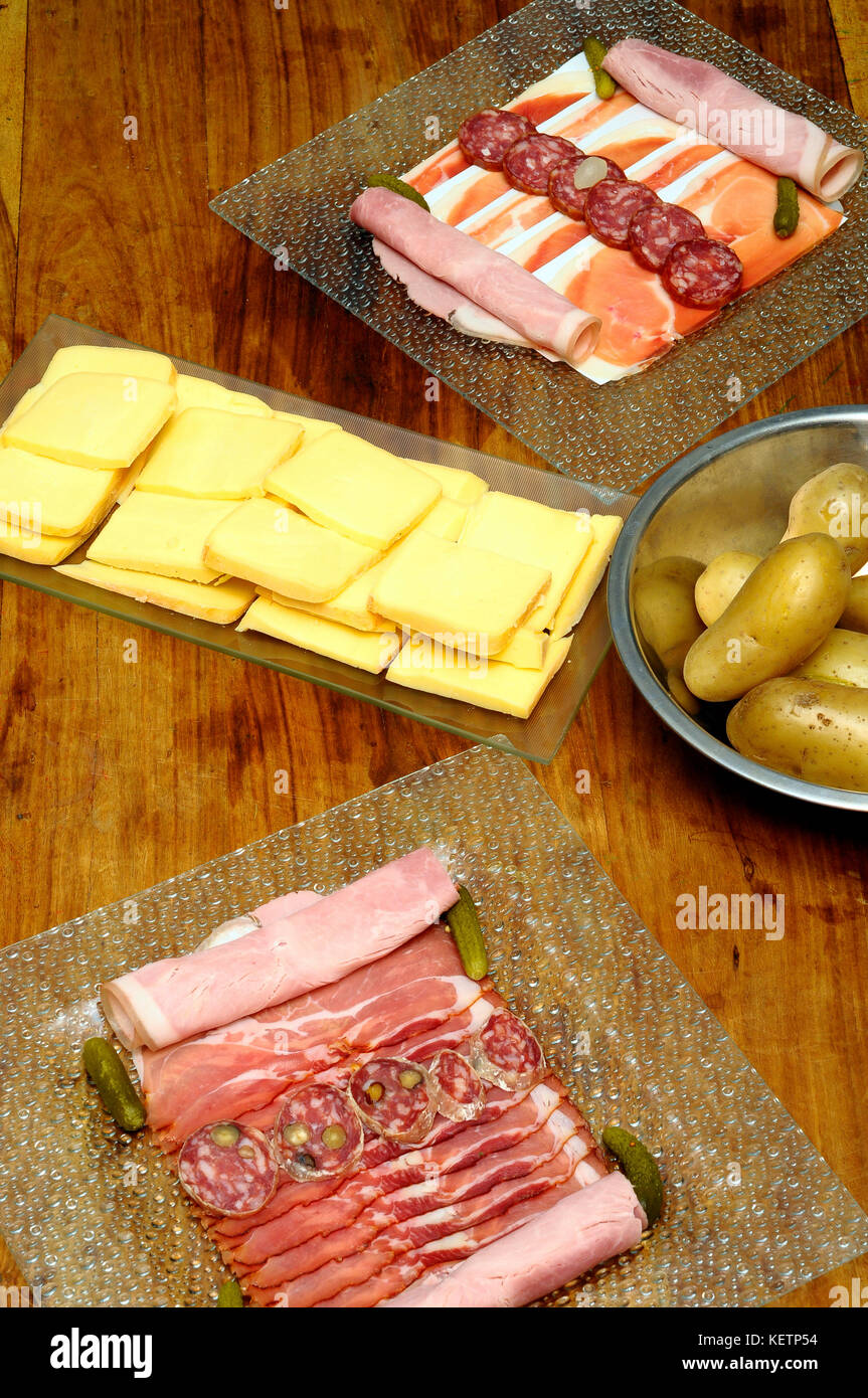 Repas raclette : fromage à raclette avec charcuterie (jambon, saucisses)