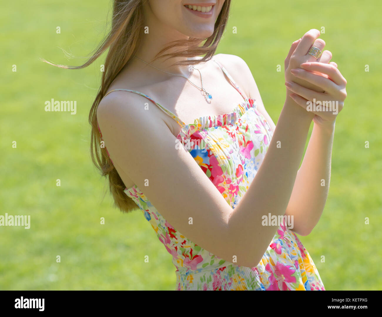 Portrait of young Beautiful woman with long hair wearing flower dress in green spring park Banque D'Images