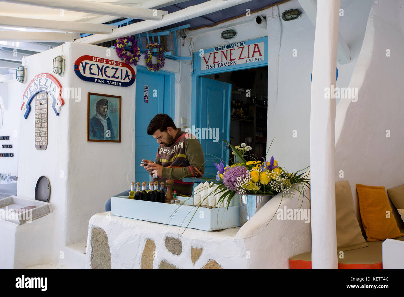 Man phoning in local frot de taverne grecque venezia à la petite Venise, ville-mykonos, Mykonos, Grèce Banque D'Images