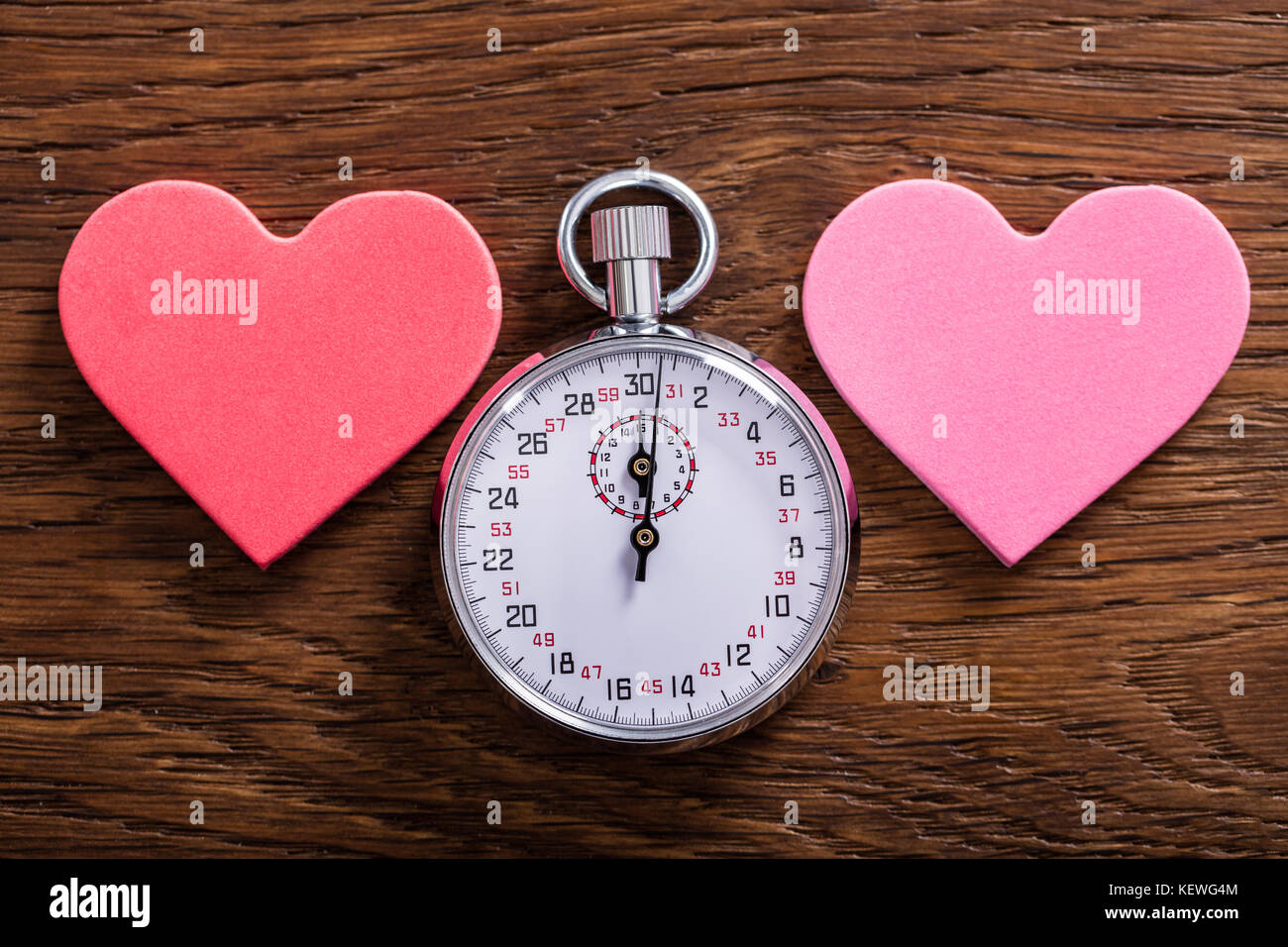 Concept de Speed Dating. Deux formes de coeur et d'un chronomètre sur un bureau en bois Banque D'Images