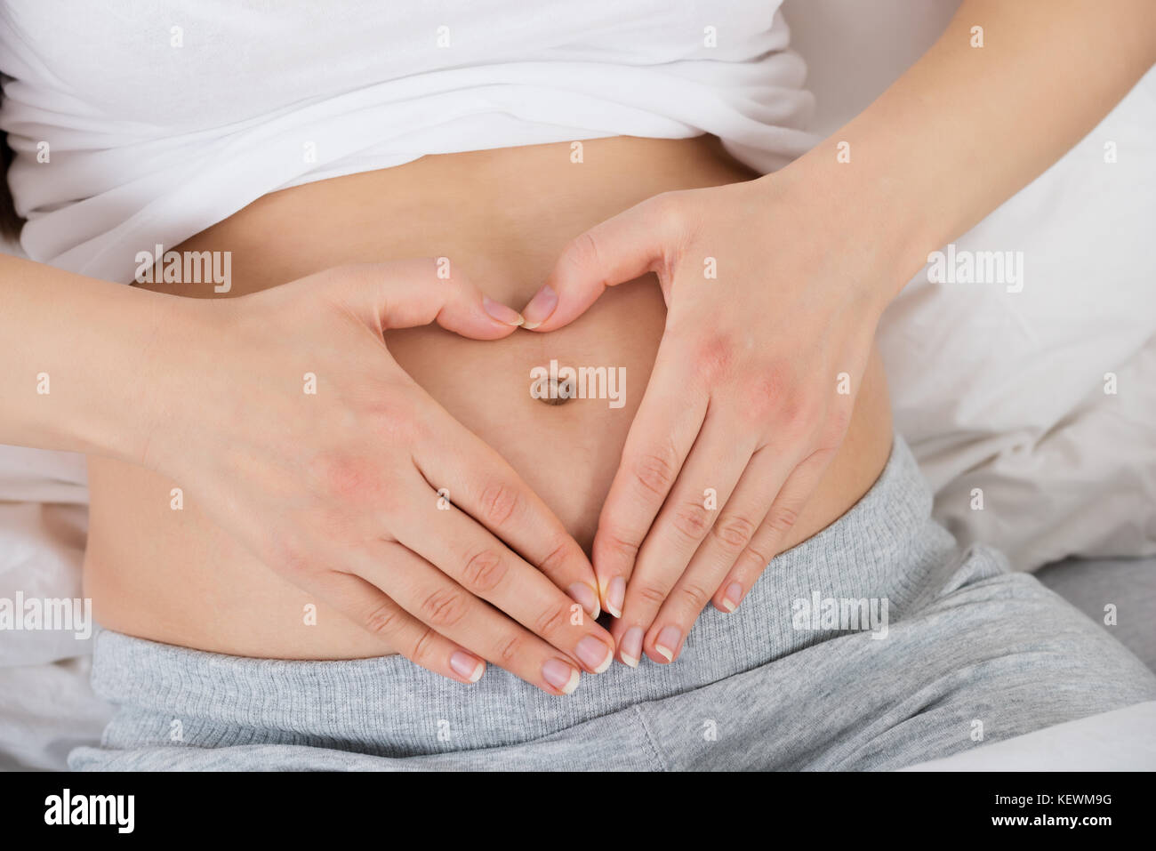 Jeune femme enceinte en forme de coeur avec les mains sur son estomac Banque D'Images