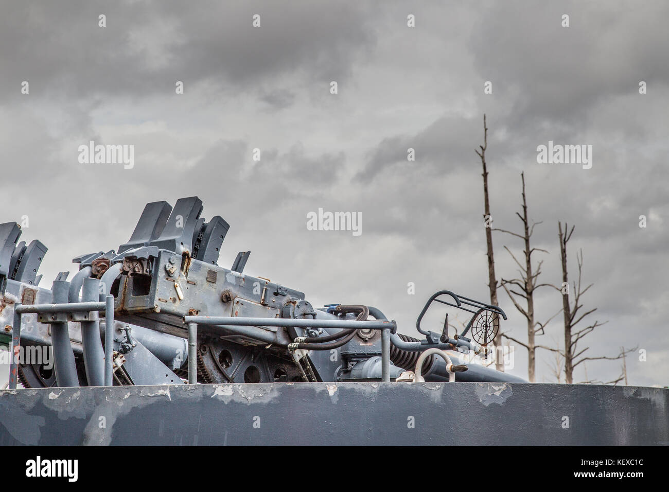 Armes à feu sur l'USS North Carolina donnent sur les arbres morts sous un ciel d'orage Banque D'Images