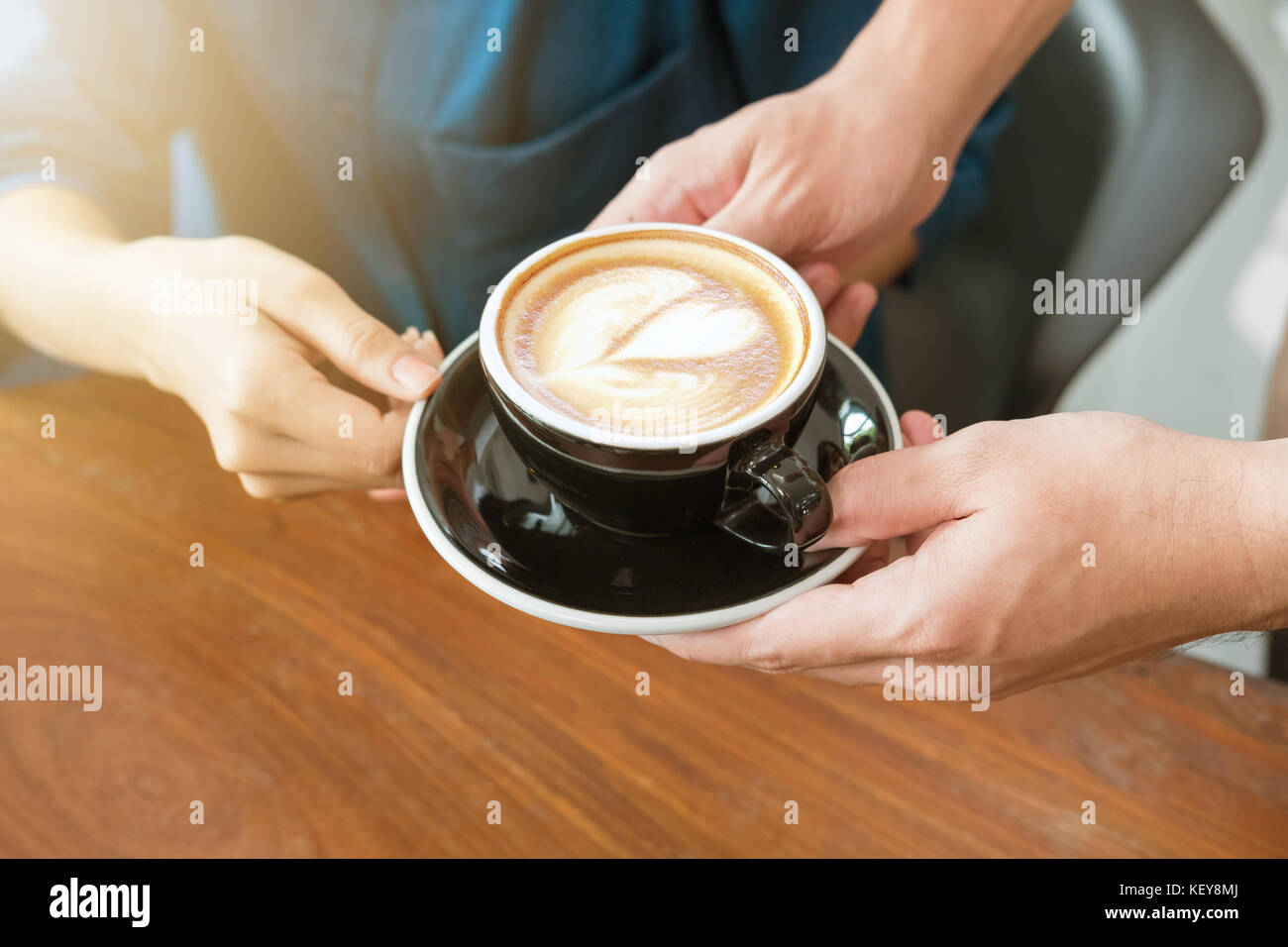 Close-up part d'une serveuse de servir une tasse de café au client. focus sélectif. Banque D'Images