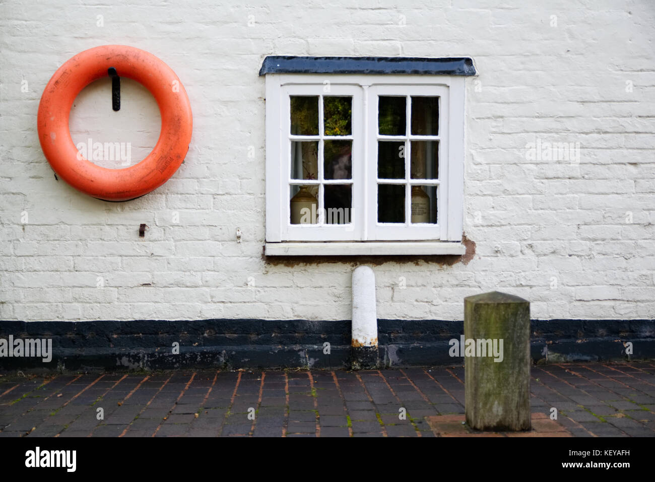 Côté canal cottage avec fenêtre et anneau de sauvetage sur le mur blanc Banque D'Images