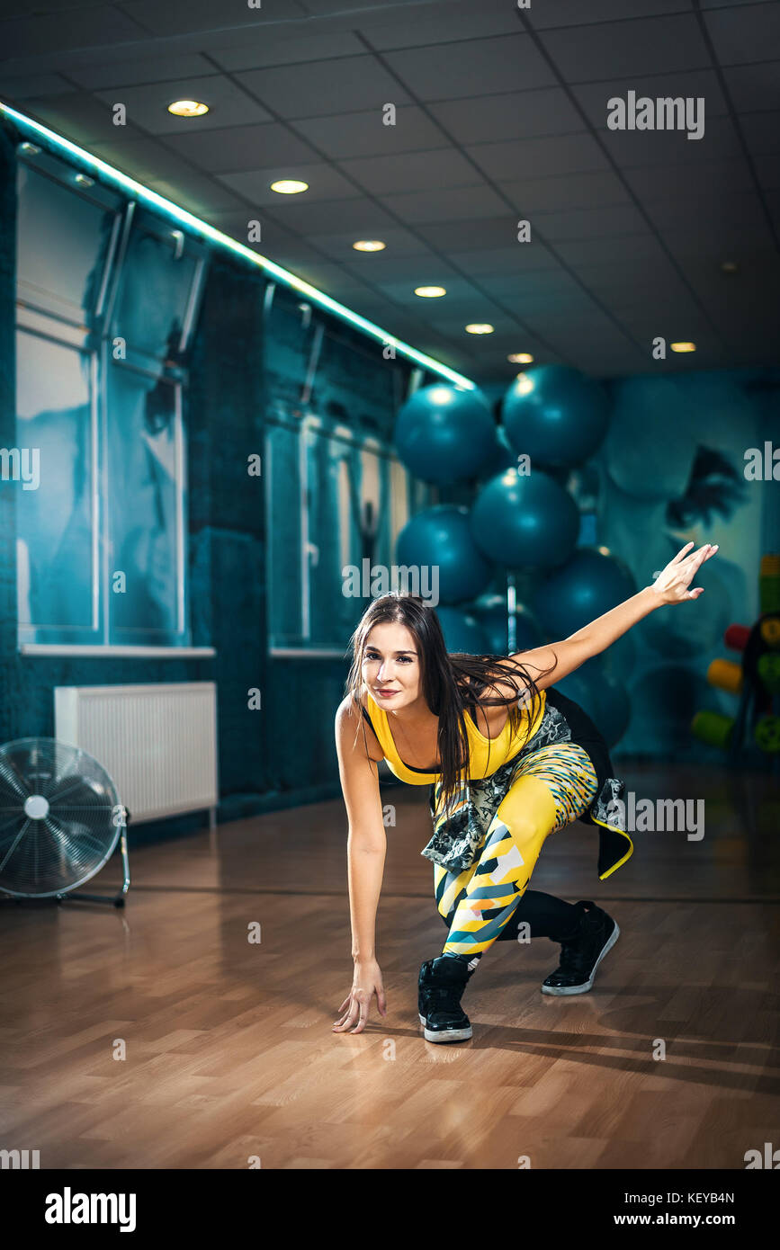 Jeune femme brune attrayante faisant l'entraînement de danse zumba seul dans le gymnase. Image tonifiée. Banque D'Images