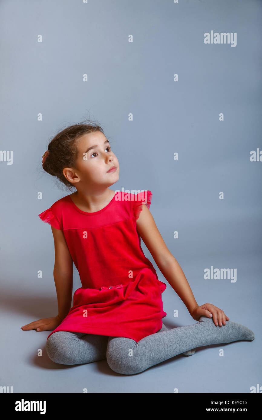 Fille calme adolescent est assis dans une robe rouge à la recherche sur le côté sur un Banque D'Images