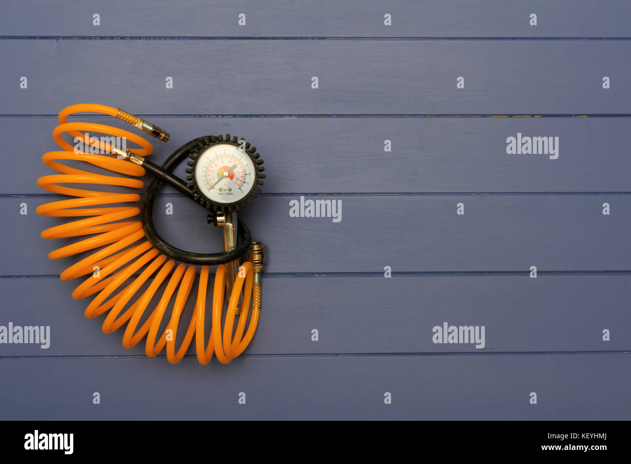 Gonflage des pneus à manomètre de pression de l'air et jaune flexible enroulé sur des planches en bleu Banque D'Images
