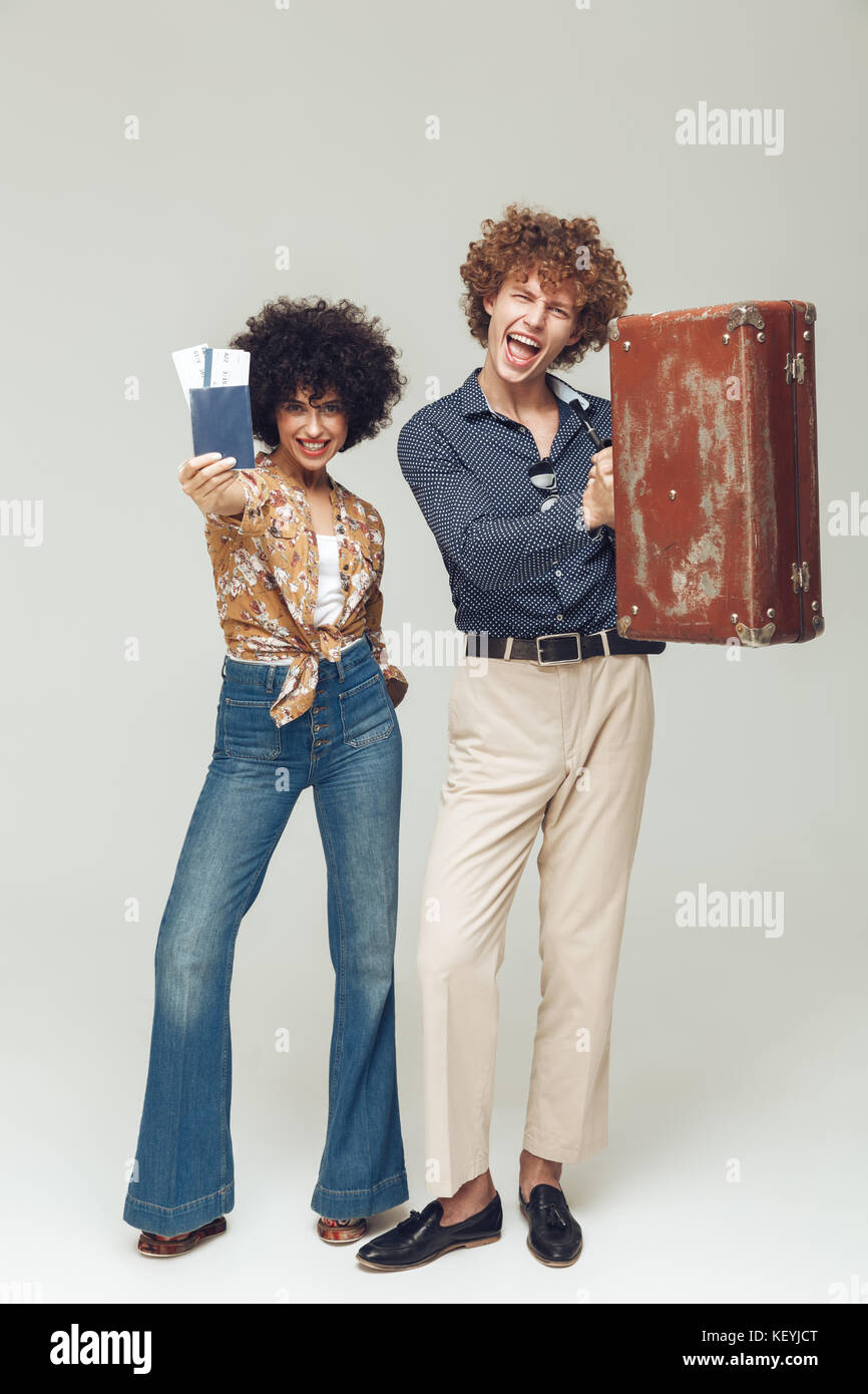 Photo de jeune couple aimant rétro isolés. Appareil photo à la holding suitcase passeport et billets. Banque D'Images