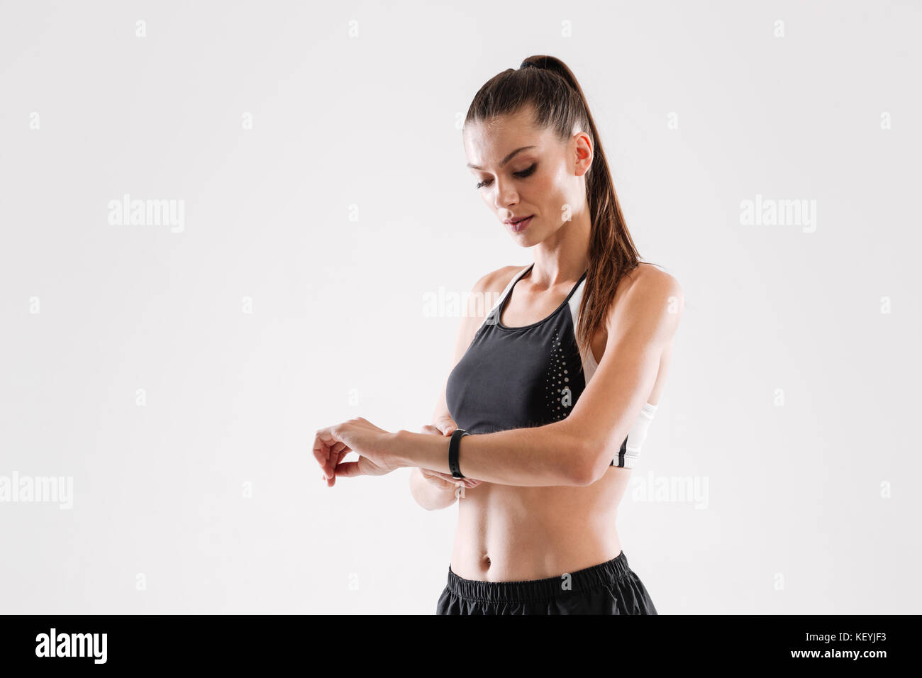 Portrait d'une très jolie femme à la remise en forme à sa montre-bracelet isolated over white background Banque D'Images