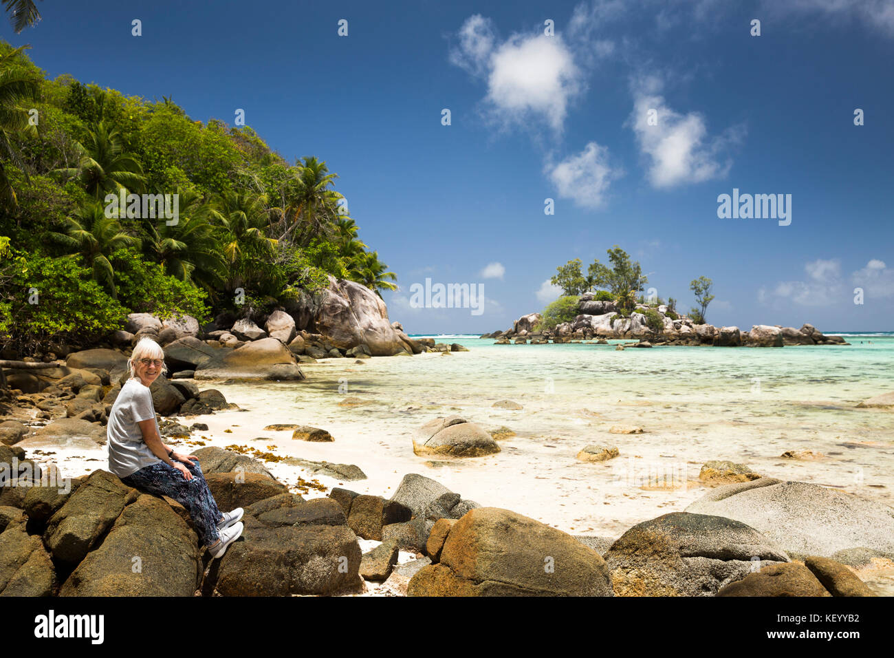 Les Seychelles, Mahe, Anse Royale, Ile Souris, plage, tourisme senior assis sur la roche de granit Banque D'Images