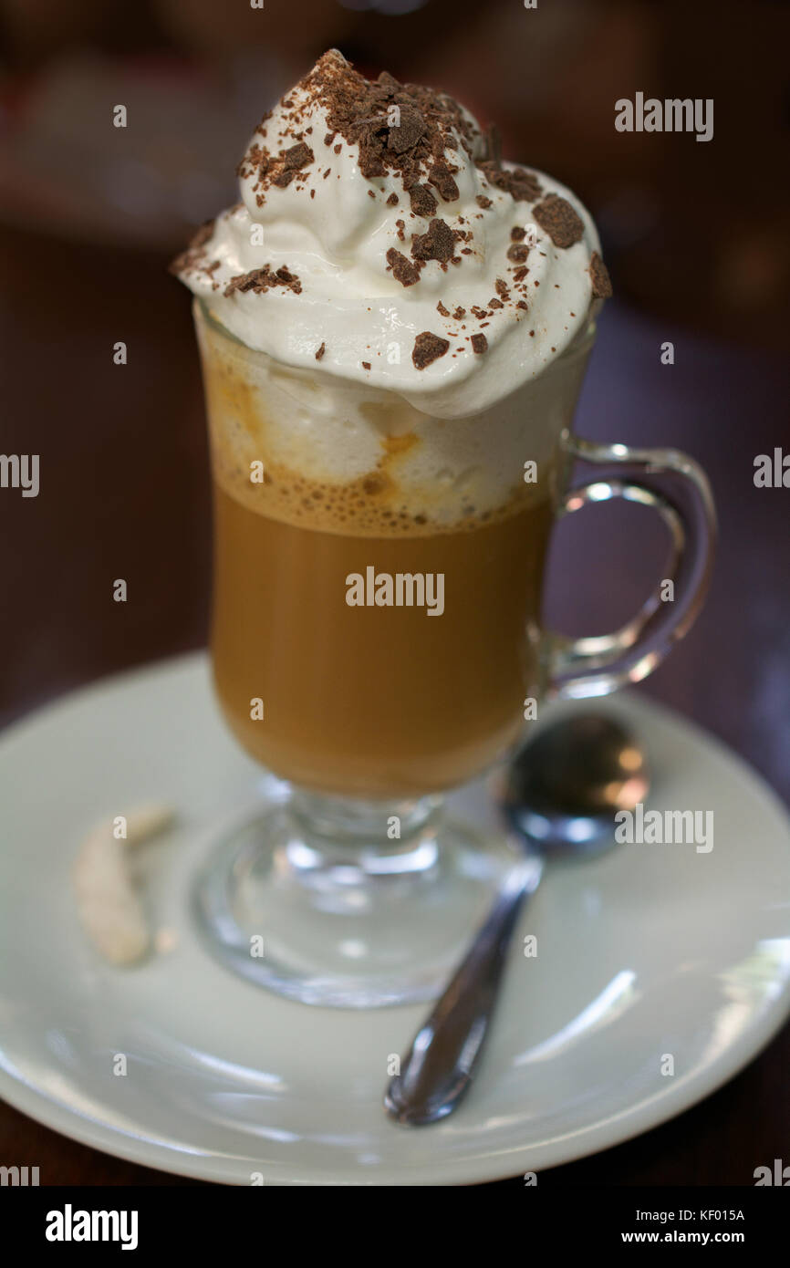 Gros plan sur un verre de café avec crème fouettée chantilly sur table marron, décoré de poudre de cacao Banque D'Images