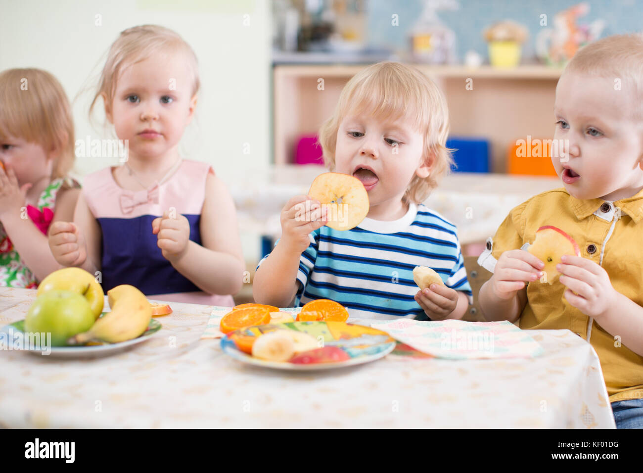 Drôle de groupe enfants manger des fruits dans le jardin d'enfants à manger Banque D'Images