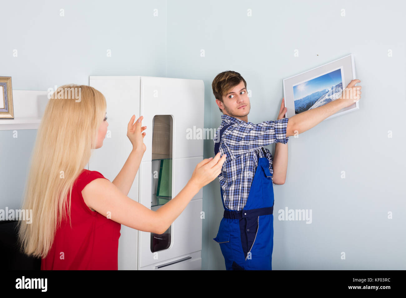 Jeune femme montrant male carpenter pour l'image à la maison Banque D'Images