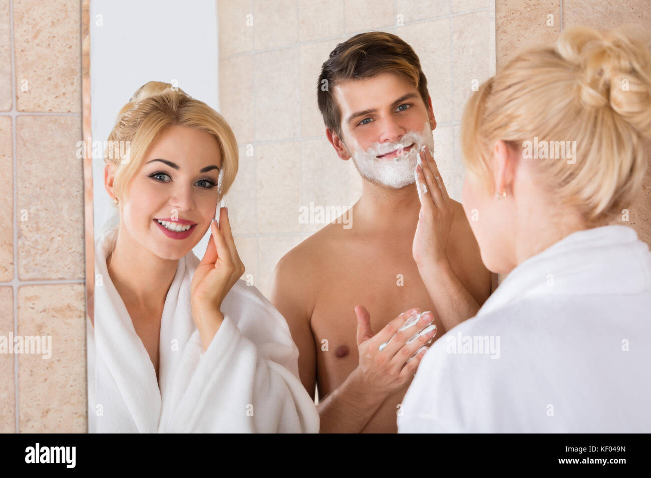 Portrait d'un homme et son épouse de rasage nettoyer son visage en miroir d'une salle de bains privative Banque D'Images