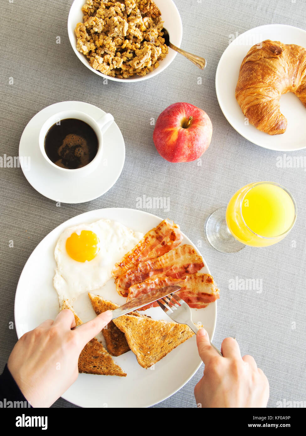 Table du petit déjeuner, femme répandre du beurre sur un toast. Banque D'Images
