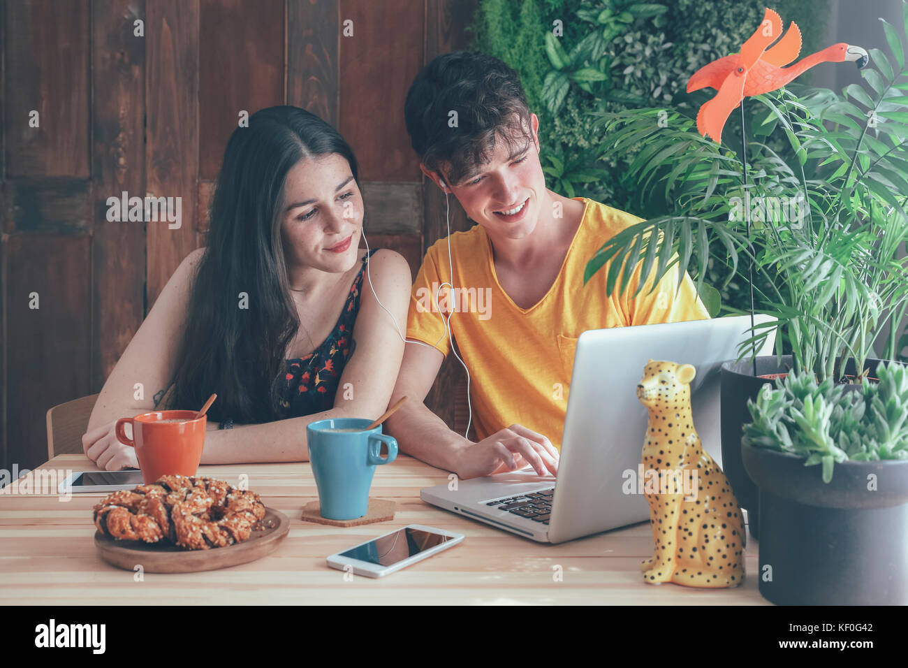 Jeune couple ayant le café et le chocolat à l'aide de tresses laptop at home Banque D'Images