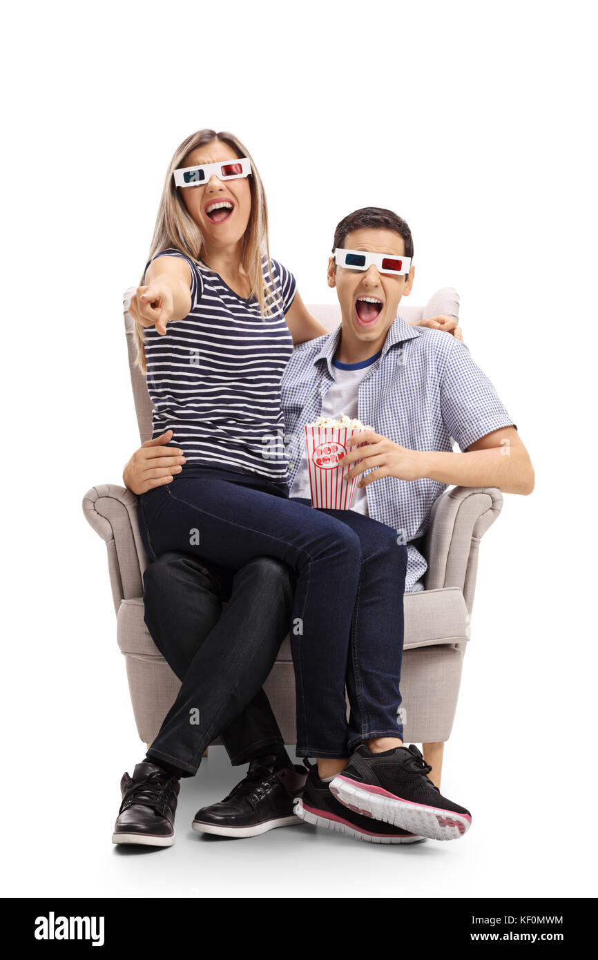 Jeune couple avec des lunettes 3D et le popcorn assise sur un fauteuil et rire isolé sur fond blanc Banque D'Images