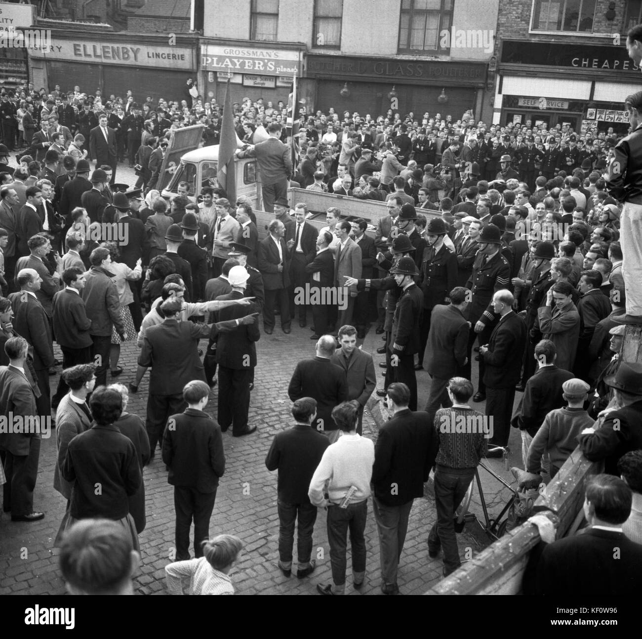 Un policier montre un doigt d'avertissement alors que des hommes dans la foule gesticulent à la réunion orageuse du mouvement syndical de Sir Oswald Mosley à Ridley Road, Dalston, Londres. Les policiers sont en service pour tenir la foule à l'écart du camion du mouvement syndical. En arrière-plan, un cordon policier épaule à épaule borde le trottoir rempli de foule. Sir Oswald a mis fin à la réunion sur avis de la police après avoir vainement tenté de parler au-dessus des cris et des bavures. Banque D'Images Un policier montre un doigt d'avertissement alors que des hommes dans la foule gesticulent à la réunion orageuse du mouvement syndical de Sir Oswald Mosley à Ridley Road, Dalston, Londres. Les policiers sont en service pour tenir la foule à l'écart du camion du mouvement syndical. En arrière-plan, un cordon policier épaule à épaule borde le trottoir rempli de foule. Sir Oswald a mis fin à la réunion sur avis de la police après avoir vainement tenté de parler au-dessus des cris et des bavures. Banque D'Images