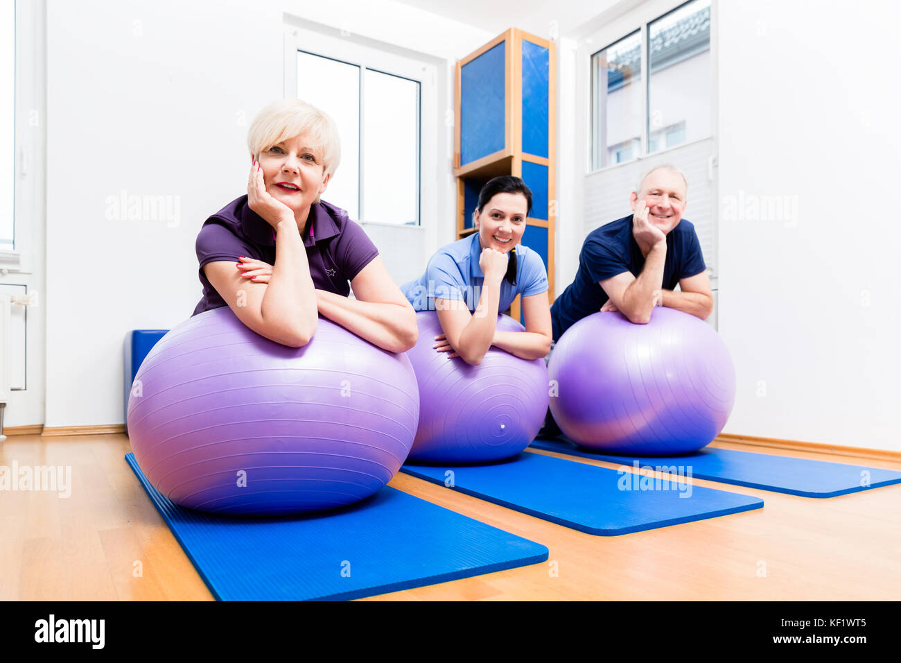 Couple physio montrant comment utiliser ballon de gymnastique pour des exercices Banque D'Images