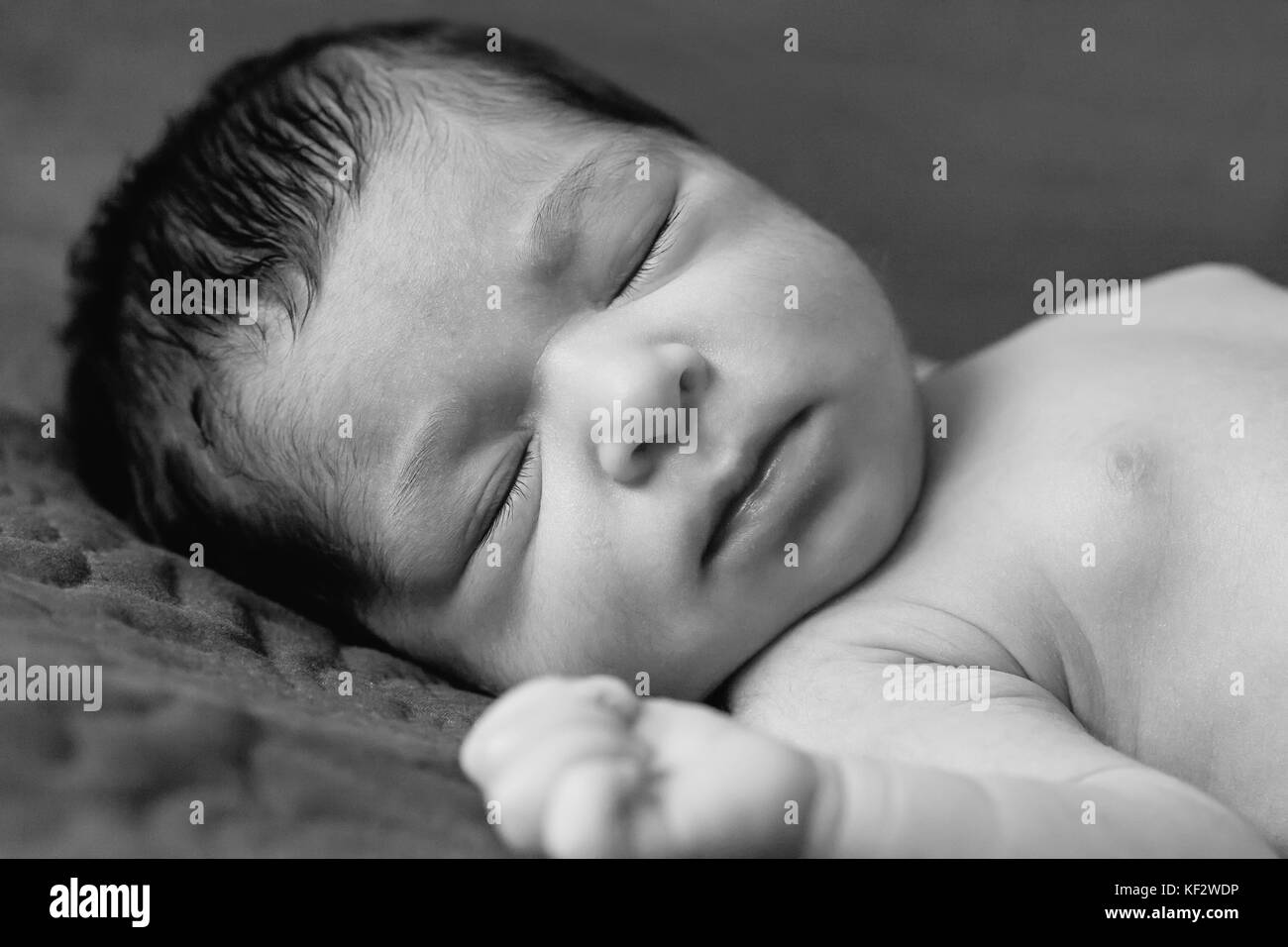 Gros plan portrait d'une petite fille de deux semaines de nouveau-né sans vêtements, nu ou nu, dormant paisiblement dans le lit Banque D'Images