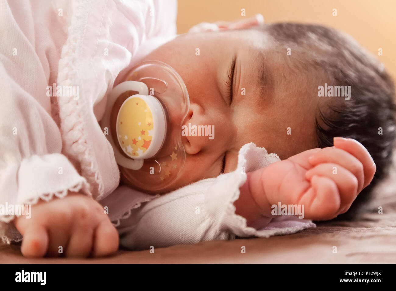 Close up portrait of a cute deux semaines Naissance bebe Fille portant des vêtements en tricot rose tendre, dormir paisiblement avec une tétine, sucette ou factice aka Banque D'Images