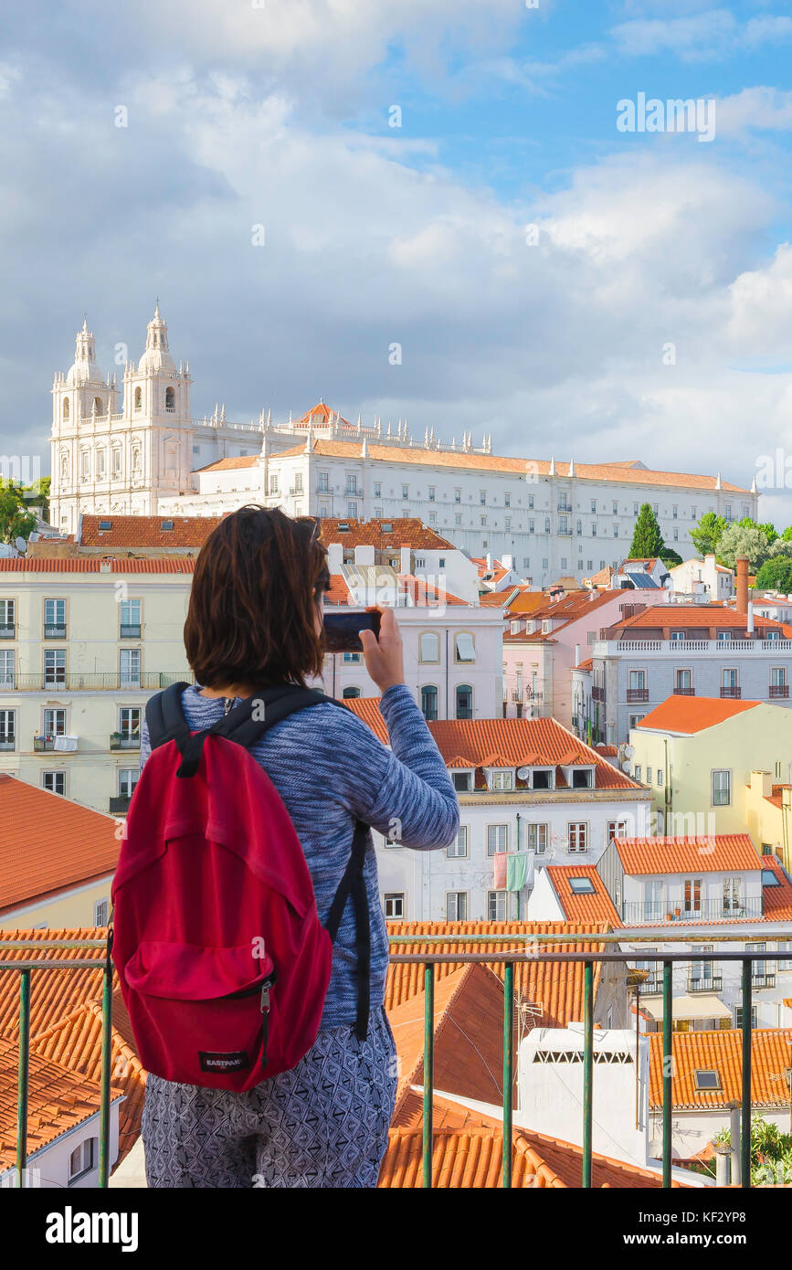 Une jeune femme voyage, vue arrière d'une touriste solo portant un sac à dos  rouge prenant une photo des bâtiments dans le quartier d'Alfama à Lisbonne,  Portugal Photo Stock - Alamy