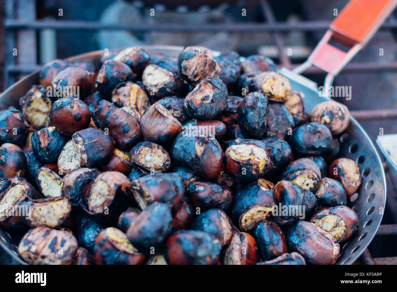 Marché de producteurs locaux bio châtaignes prêtes pour la cuisson dans une boîte en bois avec une boule ou sur un feu ouvert Banque D'Images