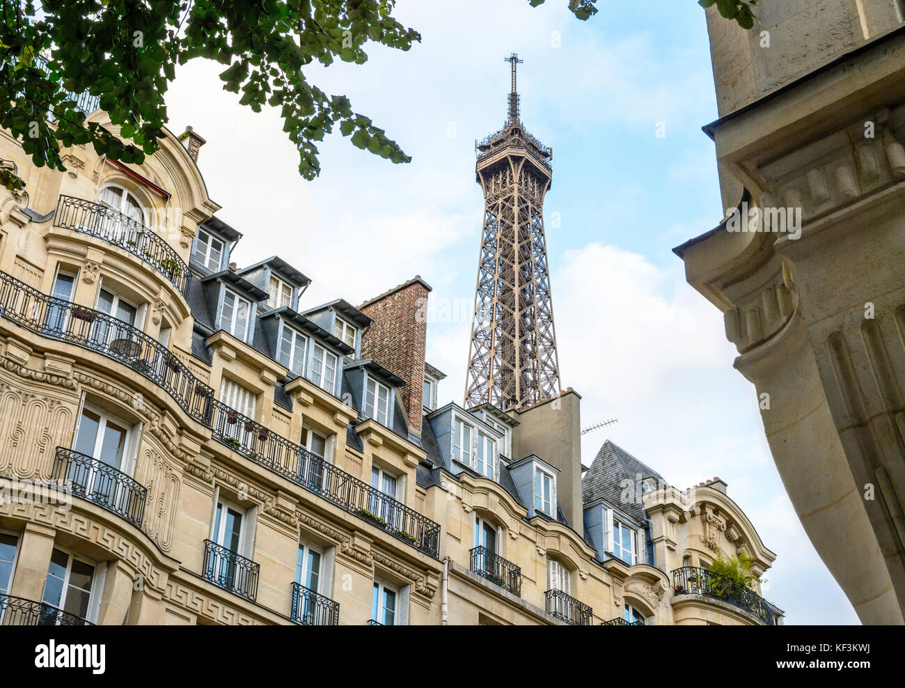 Le haut de la Tour Eiffel vu d'en bas de la rue avec le feuillage et typique des immeubles d'habitation au premier plan. Banque D'Images