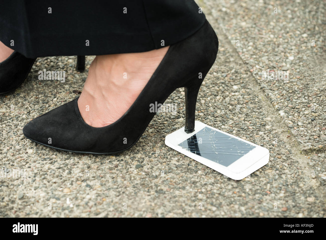 Close-up de l'écran du téléphone mobile endommagé avec talons hauts sur elle Banque D'Images