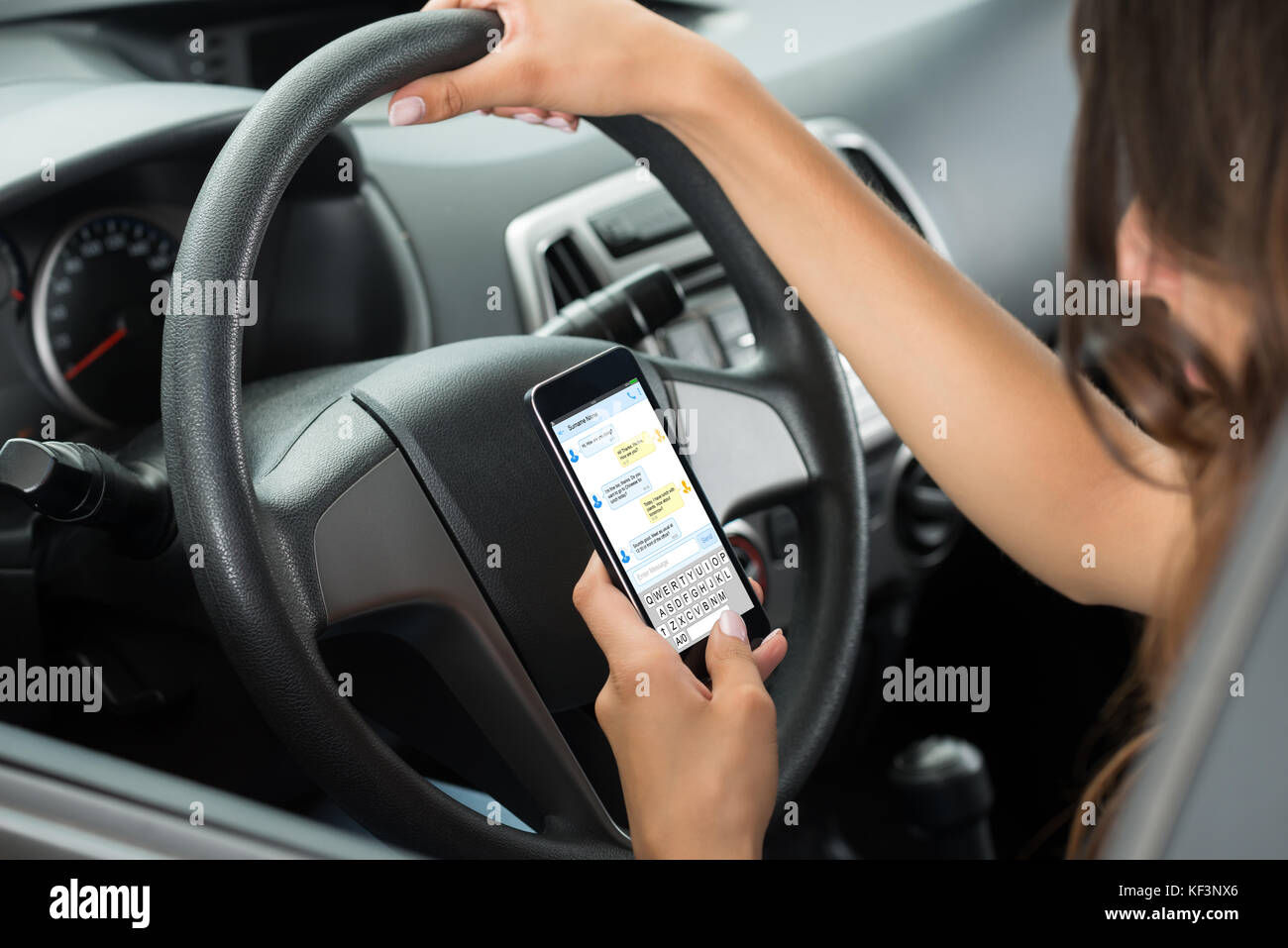 Portrait de femme assise à l'intérieur voiture tapant text message on mobile phone Banque D'Images