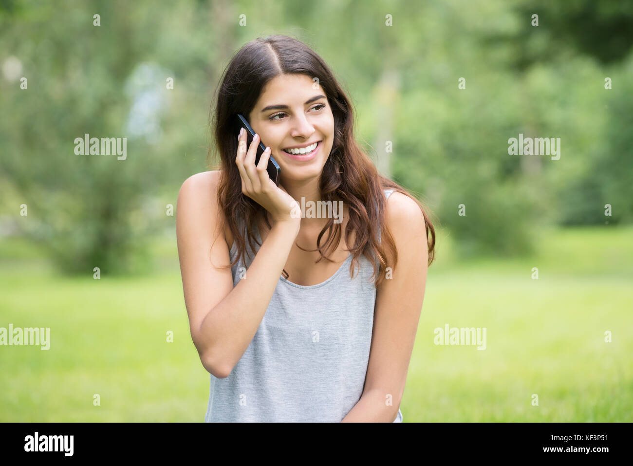 Smiling Young Woman Using Mobile Phone In Park Banque D'Images