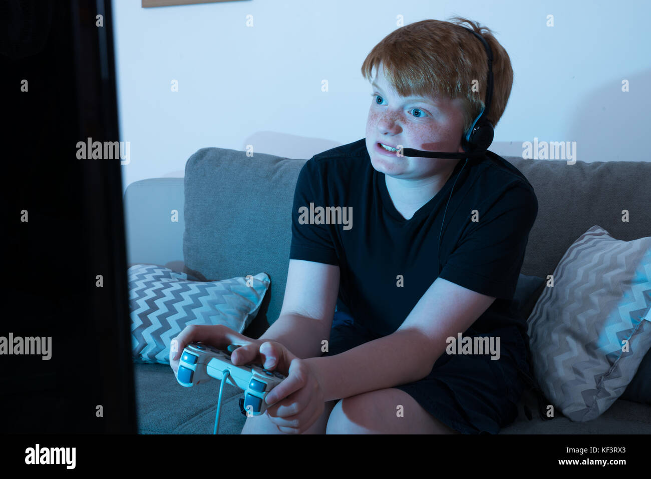 Angry boy sitting on sofa les jeux vidéo Banque D'Images