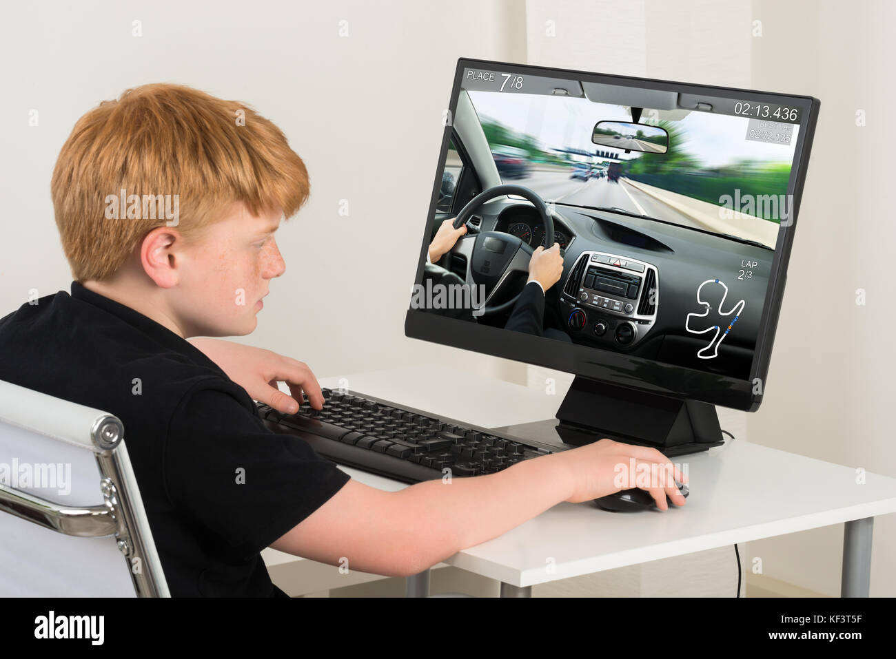 Garçon assis sur une chaise à jouer Jeu Voiture sur ordinateur à la maison Banque D'Images