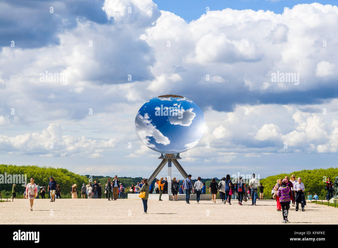 L'installation d'art dans les jardins du château de Versailles en 2015. L'art, appelé 'Sky Mirror" par l'artiste contemporain britannique Anish Kapoor, est photographié contre un blue cloudy sky, qui reflètent le ciel et le haut du château, avec les visiteurs autour de lui. Banque D'Images