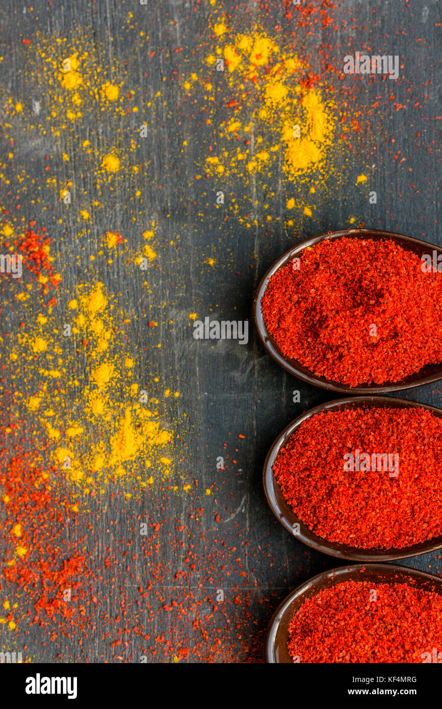 Vue de dessus de cuillères remplies d'épices paprika rouge foncé sur fond de bois recouverts de paprika et de curry en poudre Banque D'Images Vue de dessus de cuillères remplies d'épices paprika rouge foncé sur fond de bois recouverts de paprika et de curry en poudre Banque D'Images