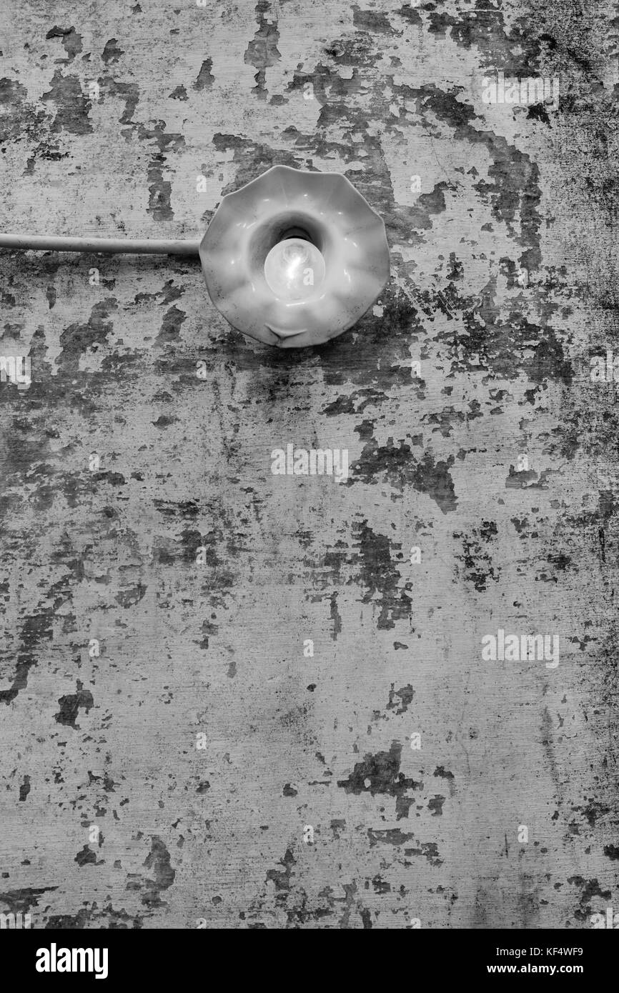 Lampe à incandescence sur vieux mur - une ampoule à incandescence éclairage lumineux sur un vieux mur ébréché. Banque D'Images