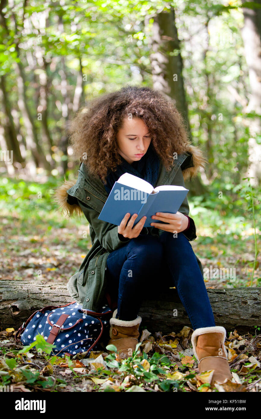 Voir l'adolescence lycéenne au livre de lecture dans le parc en automne Banque D'Images