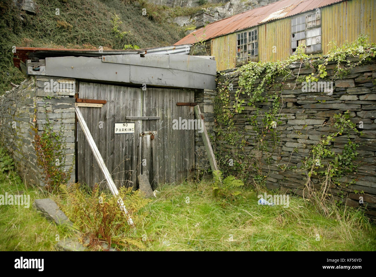 Garage désaffecté et abandonné avec allée envahie par la végétation, Blaenau Ffestiniog, pays de Galles. Banque D'Images