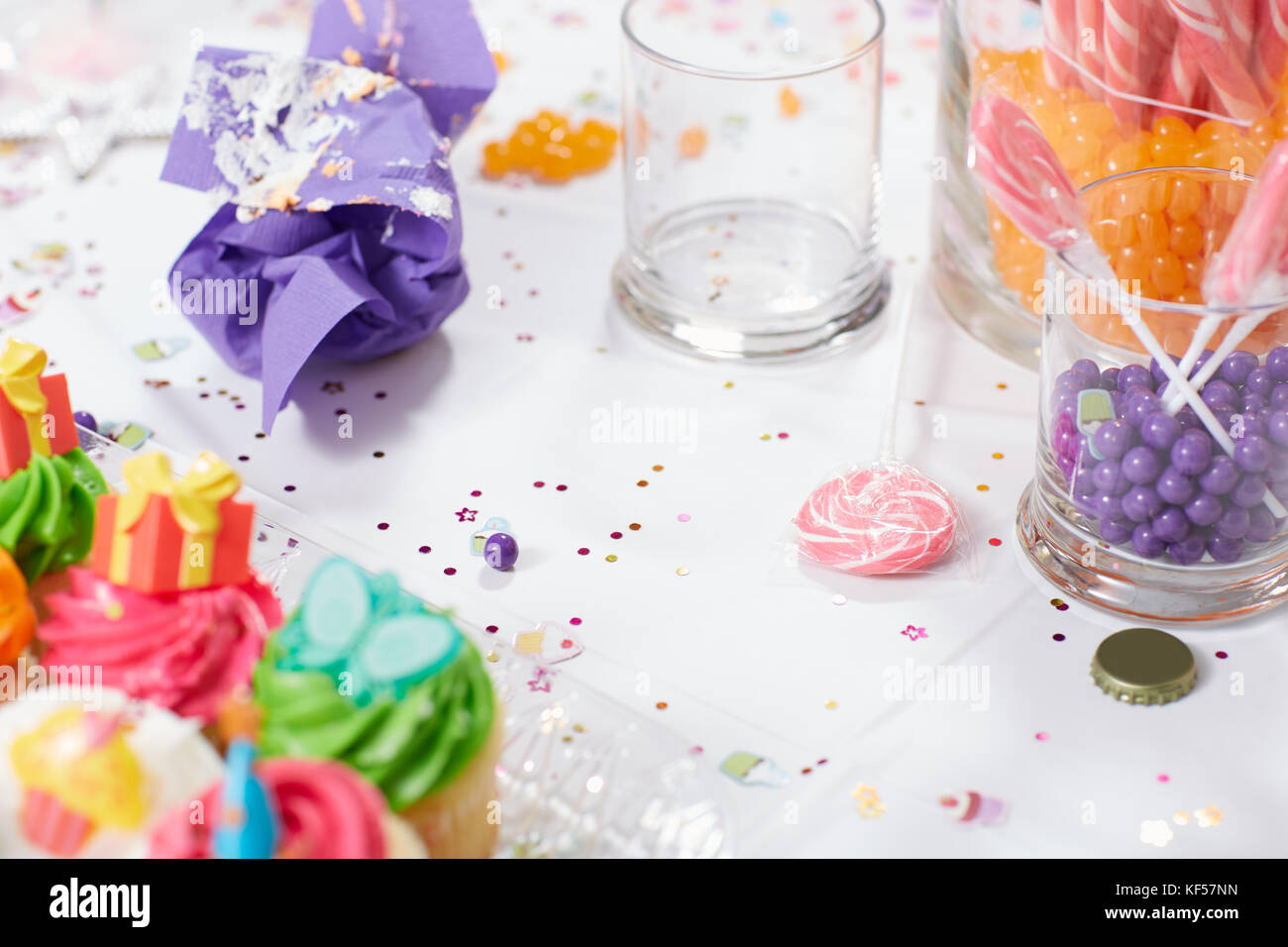 Table d'anniversaire pour les enfants avec des petits gâteaux glacés et des bonbons dans des bocaux en verre saupoudré de confettis dans une vue en gros plan Banque D'Images