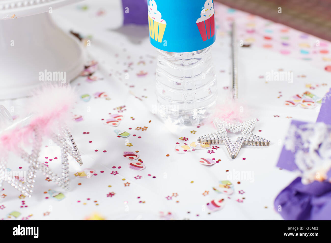 Close-up of colorful confetti à côté d'une baguette magique et une couronne sur une table de fête pour une fête d'anniversaire pour les filles avec thème princesse Banque D'Images