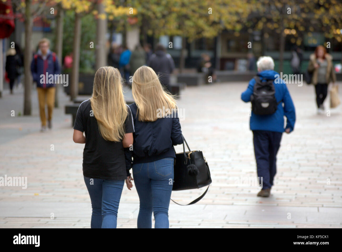 Deux jeunes soeurs filles blonde avec les cheveux droits des adolescents avec sacs à main vu de derrière Banque D'Images