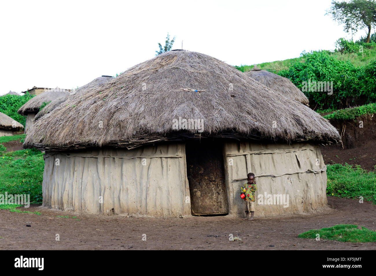 Un mignon petit garçon debout par sa famille hut dans le nord de la Tanzanie. Banque D'Images