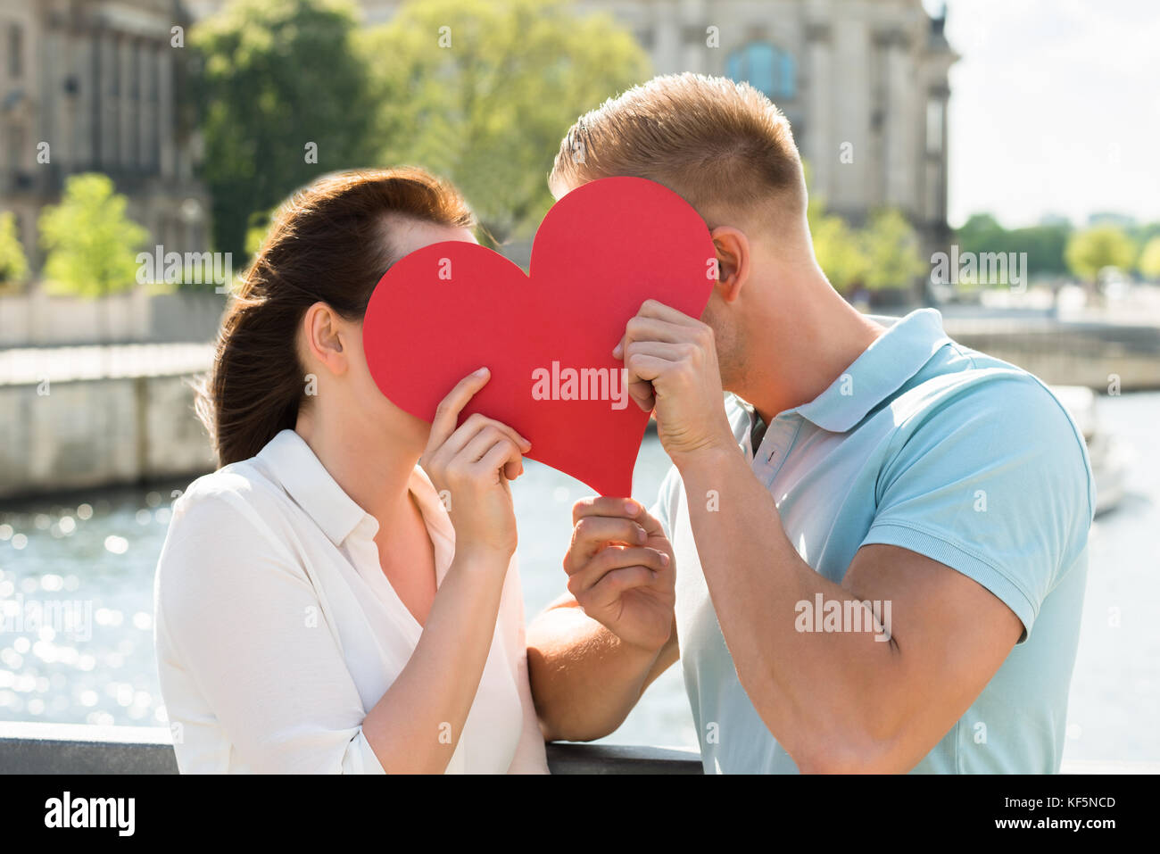 Close-up of Young Couple cache derrière forme de coeur Banque D'Images