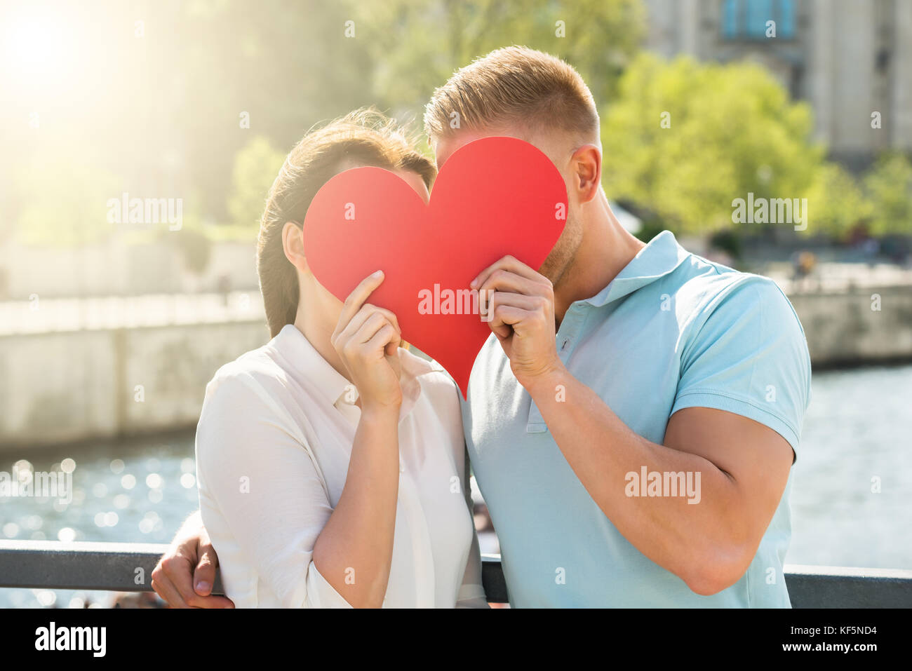 Close-up of Young Couple cache derrière forme de coeur Banque D'Images